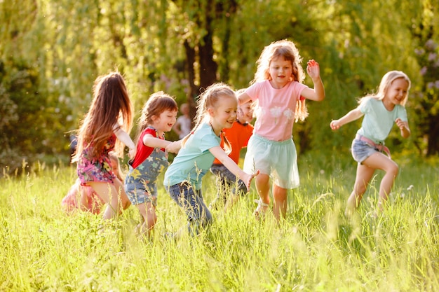 Eine Gruppe Kinder, die in den Park auf einem grünen gozon spielen und laufen.