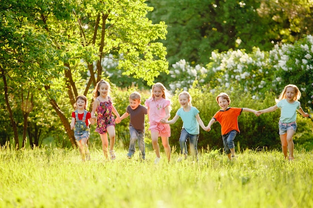 Eine Gruppe Kinder, die in den Park auf einem grünen gozon spielen und laufen.