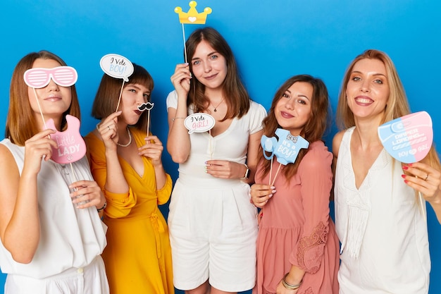 Eine Gruppe lächelnder kaukasischer weiblicher Models mit Geschlecht enthüllt einen isolierten blauen Hintergrund