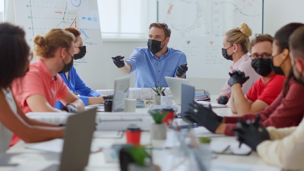 Foto eine gruppe maskierter menschen sitzt um einen tisch in einem besprechungsraum.