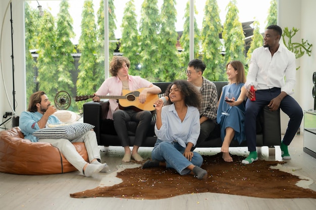 Foto eine gruppe multiethnischer freunde, die sich zu hause bei einer party amüsieren, indem sie gitarre spielen und zusammen singen