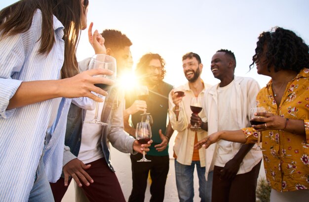 Eine Gruppe multiethnischer Freunde versammelte sich, um zu plaudern und Rotwein zu trinken, glückliche junge Leute zusammen.