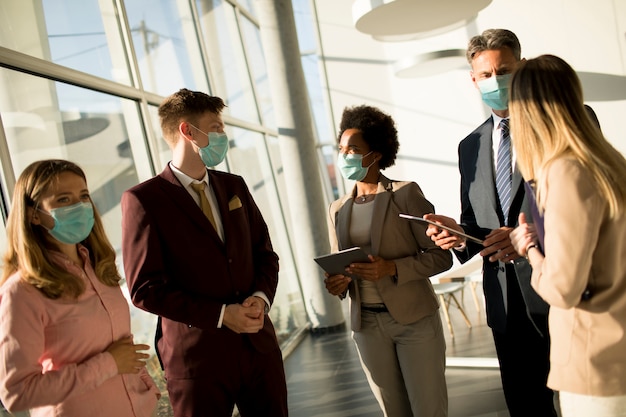 Eine Gruppe multiethnischer Geschäftsleute trifft sich und arbeitet im Büro, während sie als Schutz eine Maske tragen