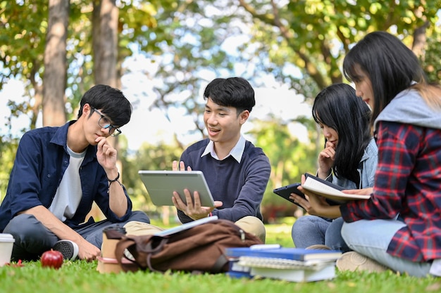 Eine Gruppe smarter junger asiatischer College-Studenten, die gemeinsam ihr Projekt im Park des Campus durchführen