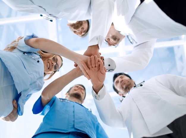 Eine Gruppe von Ärzten hält sich an den Händen. Sie demonstrieren enge Zusammenarbeit und Freundschaft. Sie arbeiten im Krankenhaus