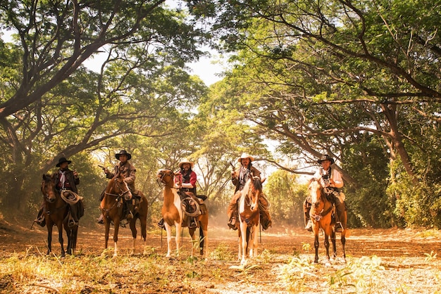 Eine Gruppe von Cowboys, die auf Pferden reiten und eine Waffe in der Hand halten, ist bereit zum Schießen