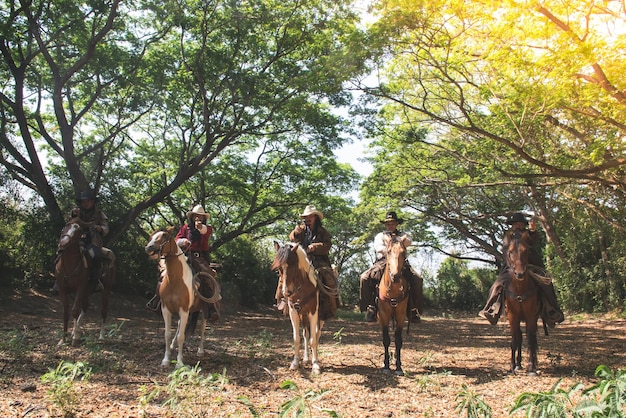 Eine Gruppe von Cowboys, die auf Pferden reiten und eine Waffe in der Hand halten, ist bereit zum Schießen