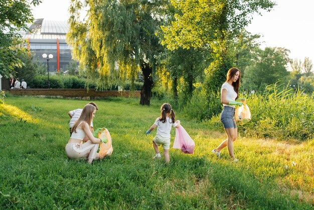 Eine Gruppe von Erwachsenen und Kindern beschäftigt sich bei Sonnenuntergang gemeinsam mit der Müllabfuhr im Park Umweltschutz Abfallrecycling Sortierung von Müll