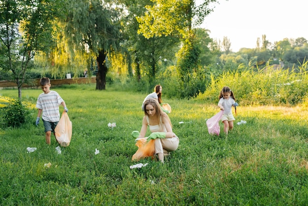 Eine Gruppe von Erwachsenen und Kindern beschäftigt sich bei Sonnenuntergang gemeinsam mit der Müllabfuhr im Park Umweltschutz Abfallrecycling Sortierung von Müll