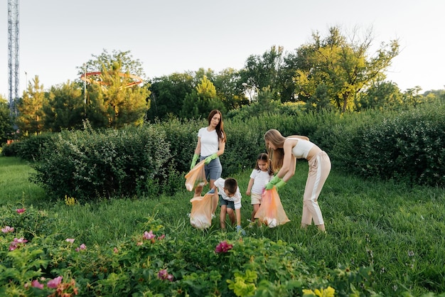 Eine Gruppe von Erwachsenen und Kindern beschäftigt sich bei Sonnenuntergang gemeinsam mit der Müllabfuhr im Park Umweltschutz Abfallrecycling Sortierung von Müll