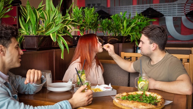 Eine Gruppe von Freunden, die sich in einer Kneipe ausruhen. Essen, Trinken, Essen auf dem Tisch. Freundschaft