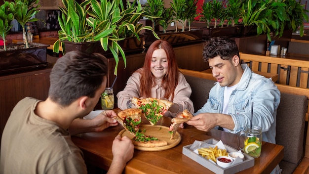 Eine Gruppe von Freunden, die sich in einer Kneipe ausruhen. Essen, Trinken, Essen auf dem Tisch. Freundschaft