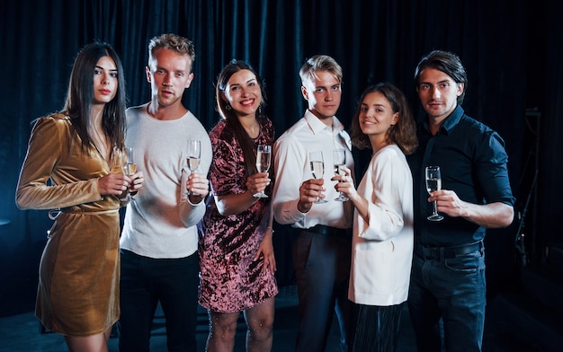 Eine Gruppe von Freunden in festlicher Kleidung feiert zusammen drinnen.