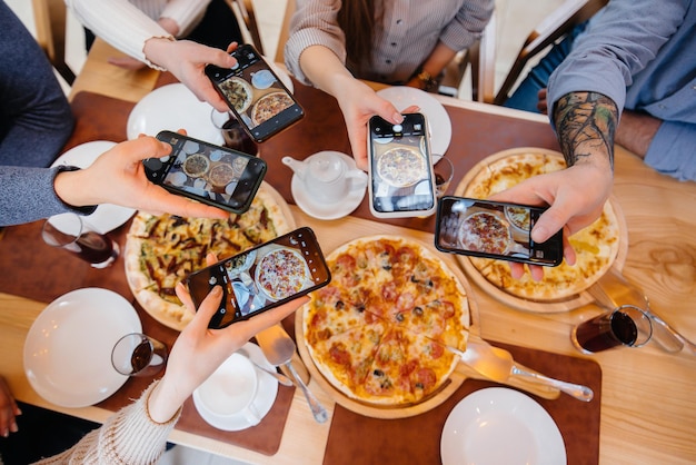 Eine Gruppe von Freunden macht ein Nahaufnahmenfoto einer leckeren Pizza für den Blog Pizzeria.