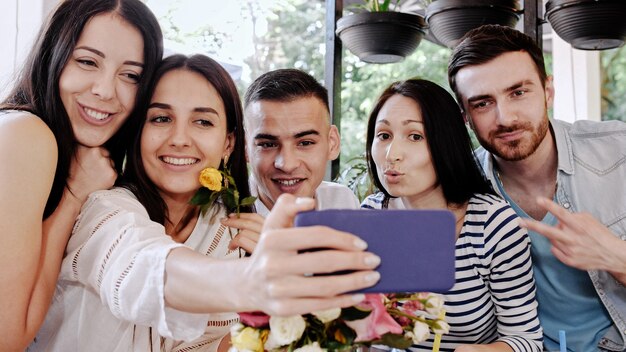 Eine Gruppe von Freunden macht Selfies in einem Café