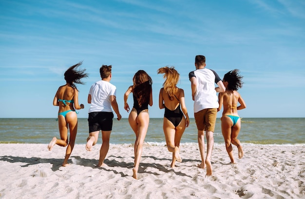 Eine Gruppe von Freunden rennt zum Schwimmen ins Meer. Sommerferien, Entspannungs- und Lifestyle-Konzept