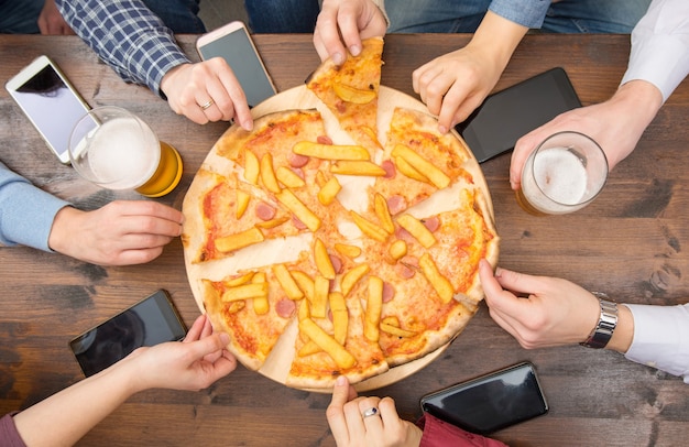 Eine Gruppe von Freunden trinkt Bier, isst Pizza, redet und lächelt, während sie sich zu Hause ausruhen