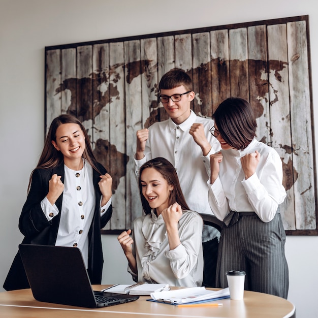 Eine Gruppe von Geschäftsleuten, die in einem Büro bei einer gemeinsamen Besprechung arbeiten, machen eine erfolgreiche Geste