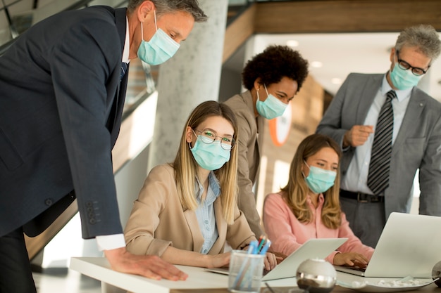 Eine Gruppe von Geschäftsleuten trifft sich und arbeitet im Büro und trägt Masken zum Schutz vor dem Koronavirus