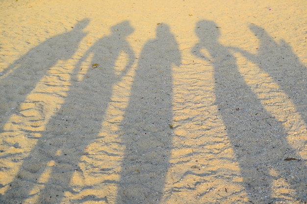 Foto eine gruppe von glücklichen reisenden beschattet den strandsand zur sonnenuntergangszeit unter verwendung für texturhintergrund.