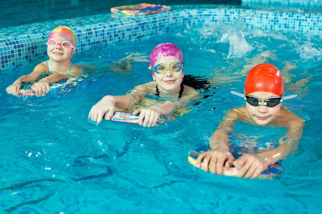 Eine Gruppe von Jungen und Mädchen trainiert und lernt mit einem Lehrer im Pool schwimmen