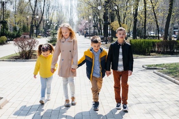 Eine Gruppe von Kindern spielt zusammen und geht Händchen haltend im Park spazieren. Freunde, Kinder.