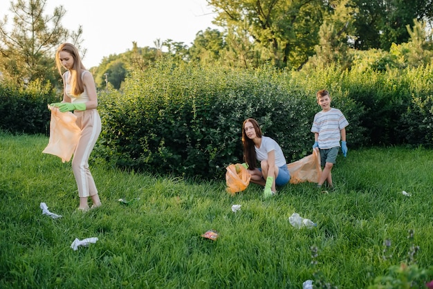 Eine Gruppe von Mädchen mit Kindern bei Sonnenuntergang beschäftigt sich mit der Müllabfuhr im Park. Umweltschutz, Recycling.