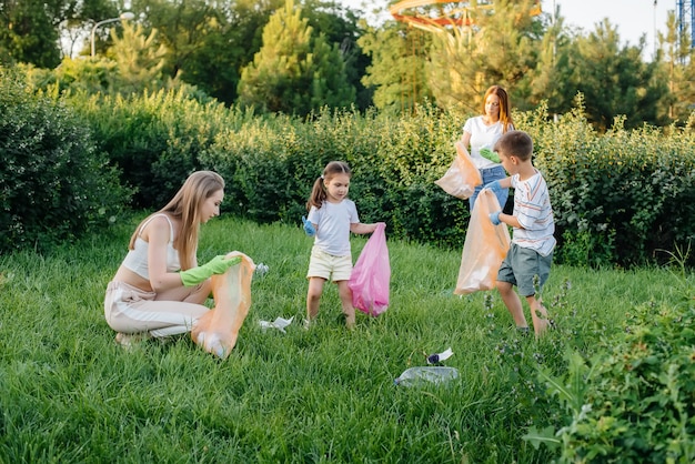 Eine Gruppe von Mädchen mit Kindern bei Sonnenuntergang beschäftigt sich mit der Müllabfuhr im Park. Umweltschutz, Recycling.