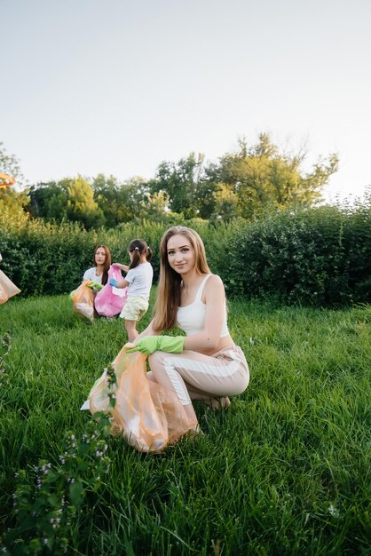 Eine Gruppe von Mädchen mit Kindern beschäftigt sich bei Sonnenuntergang mit der Müllabfuhr im Park. Umweltschutz, Recycling.