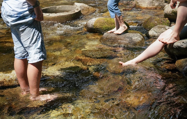 Eine Gruppe von Menschen, die in einem Waldfluss spazieren gehen oder ihre nackten Füße kühlen, nur auf den Beinen