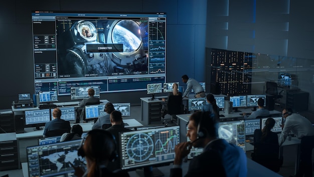 Eine Gruppe von Menschen im Missionskontrollzentrum stellt eine erfolgreiche Videoverbindung mit einem Astronauten an Bord einer Raumstation her.