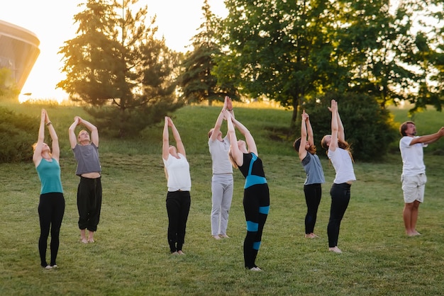 Eine Gruppe von Menschen macht Yoga im Park bei Sonnenuntergang