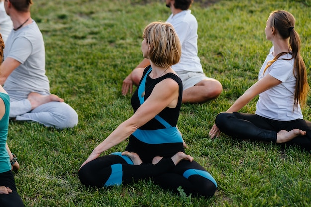 Eine Gruppe von Menschen macht Yoga im Park bei Sonnenuntergang