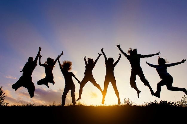 Foto eine gruppe von menschen springt gegen den sonnenuntergang