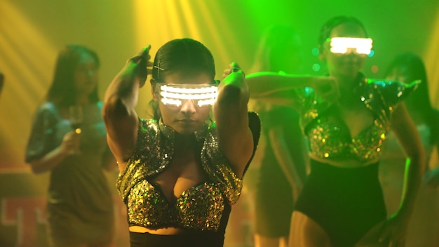 Eine Gruppe von Menschen tanzt im Disco-Nachtclub im Rhythmus der Musik von DJ auf der Bühne