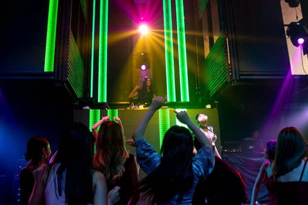 Eine Gruppe von Menschen tanzt im Disco-Nachtclub im Takt der Musik von DJ auf der Bühne