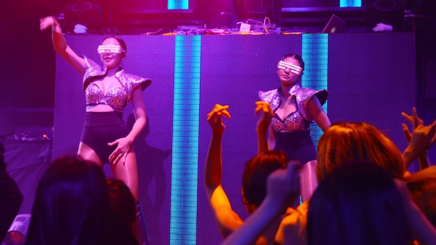Eine Gruppe von Menschen tanzt im Disco-Nachtclub im Takt der Musik von DJ auf der Bühne
