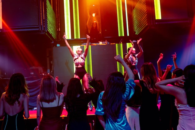 Eine Gruppe von Menschen tanzt im Disco-Nachtclub zum Beat der Musik vom DJ auf der Bühne