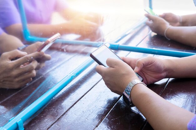 Eine gruppe von personen, die ein smartphone mit einer trennwand zwischen ihnen verwenden konzept der physischen trennung zur infektionskontrolle, um die ausbreitung des covid19-conoravirus zu stoppen oder zu verlangsamen