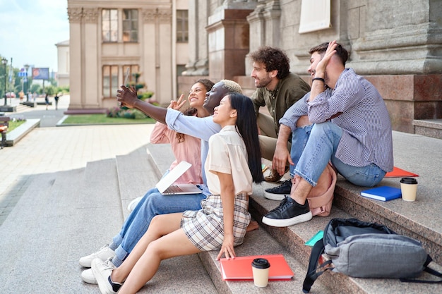 Eine Gruppe von Studenten, die auf den Stufen sitzen und sich über eine Videoverbindung unterhalten