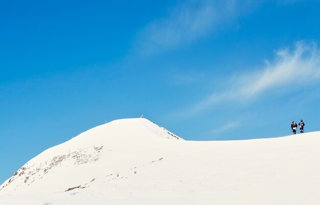 Eine Gruppe von Wanderern, die an einem sonnigen Wintermorgen einen schneebedeckten Berg besteigen