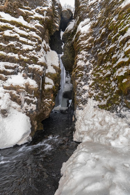 Eine Gruppe von Wanderern, die zwischen den Felsen eines zugefrorenen Flusses spazieren gehen und sehr darauf achten, nicht zu fallen