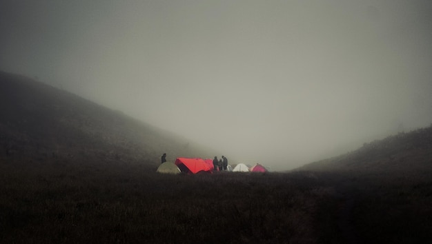 Foto eine gruppe von zelten wird in einer nebligen landschaft aufgebaut.