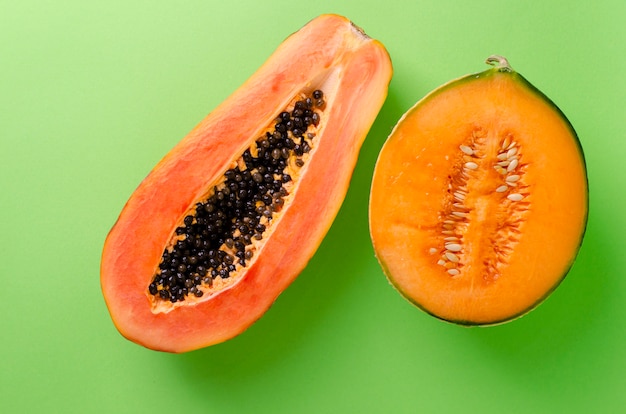 Eine Hälfte der reifen frischen Papaya und der Melone auf Grün