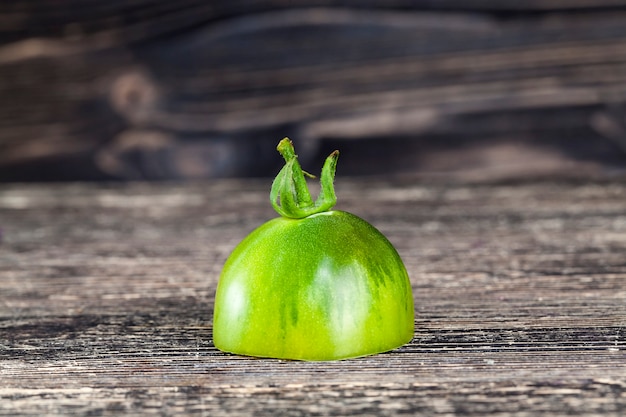 Eine halbe grüne Tomate auf einem schwarz gestrichenen Brett, Nahaufnahme