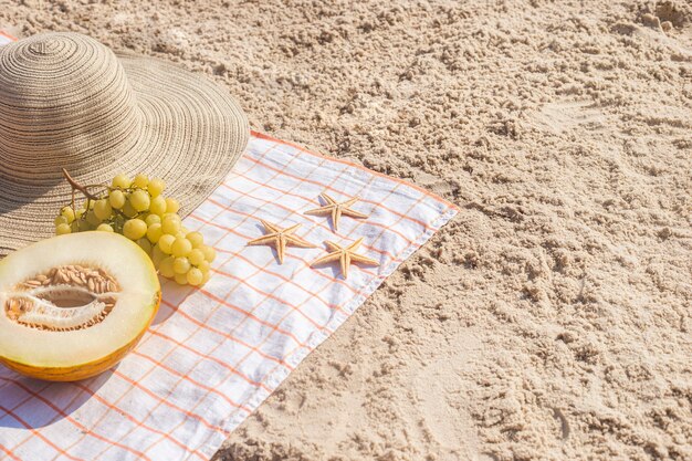 Eine halbe Melone, Trauben, Seesterne am Strand. Ansicht von oben, flach.