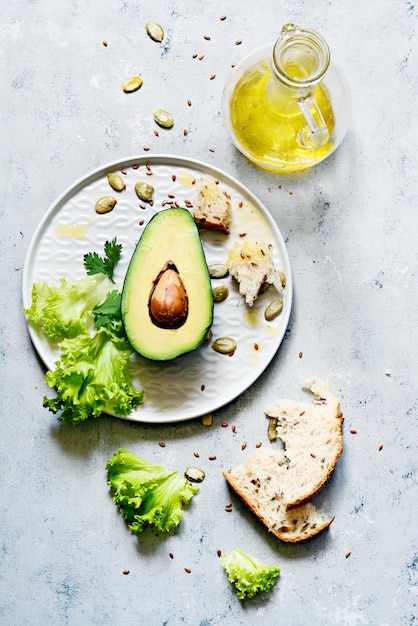 Eine halbe reife Avocado mit Samen und Salat auf einem Teller auf grauem Grund. Avocadosalat Flach legen. Lebensmittelkonzept. Draufsicht.