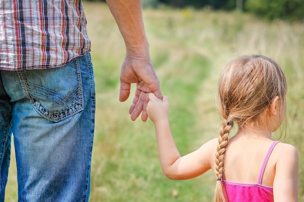 Eine Hand des glücklichen Kindes und der Eltern über die Natur im Parkfamilienkonzept