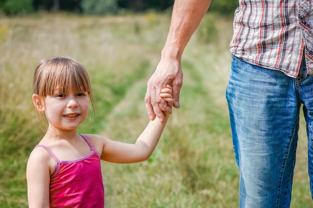 Eine Hand des glücklichen Kindes und der Eltern über die Natur im Parkfamilienkonzept