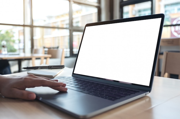 eine Hand, die das Laptop-Touchpad mit leerem weißen Desktop-Bildschirm benutzt und berührt, während sie im Büro sitzt